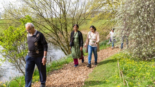 Three people walking along a riverside path in the spring